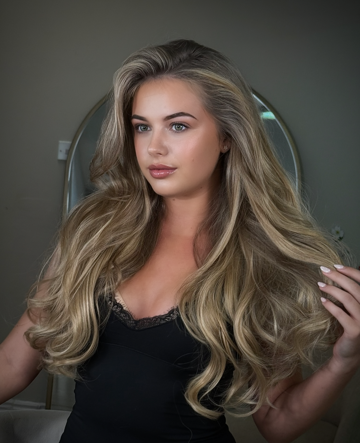 Woman with long, wavy blonde hair in front of a mirror.